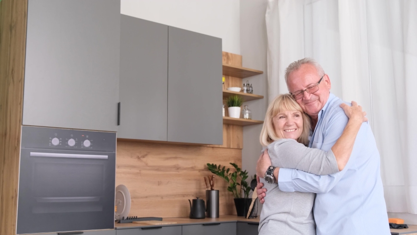 Happy senior couple dancing at home in the kitchen, they are laughing and hugging while relaxing Royalty-Free Stock Footage #1092187463
