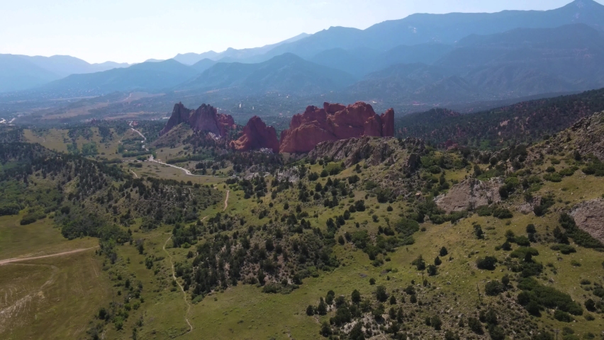 Aerial drone shot flying around Garden of the Gods rock formations with mountain silhouettes in background in Colorado Springs, Colorado, USA