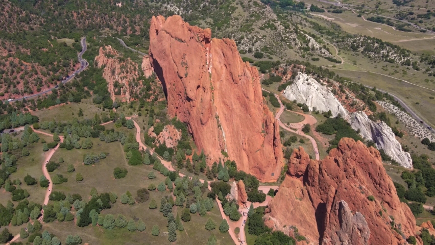 Aerial drone shot flying around Garden of the Gods rock formations with mountain silhouettes in background in Colorado Springs, Colorado, USA