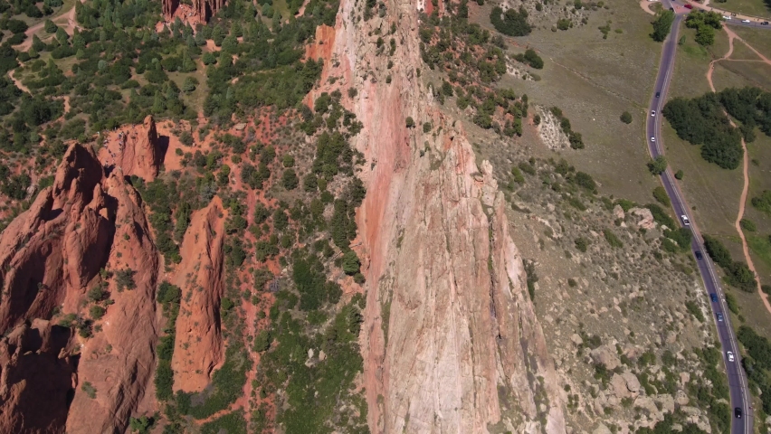 Aerial drone shot flying around Garden of the Gods rock formations with mountain silhouettes in background in Colorado Springs, Colorado, USA
