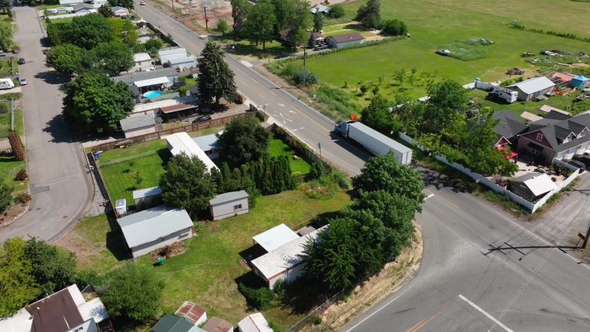 Aerial shot following a semi truck driving in a suburban area to its next delivery.
