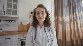 POV of therapist giving recommendations to patient on video call. Woman with stethoscope talks looking in camera sitting at kitchen table closeup