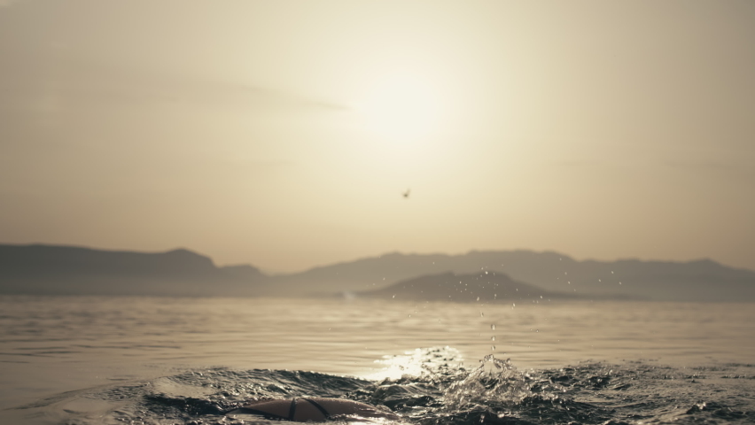 Slow motion video of a girl splashing water on her hair. Woman swims and fan in the ocean. Summer vacation joy and relaxation. High quality 4k footage