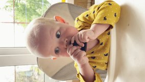 cute hungry kid eating a plastic bottle cap while sitting at the table. The child is ready to eat.vertical video