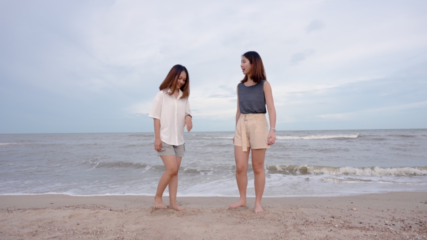 4K, Slow motion,  A close friend of a young Asian female tourist is happily jumping on the beach. A beachfront beach that is a tourist attraction for tourists on vacation.
