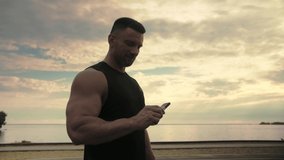 Аthletic man eating a protein bar after a workout against the backdrop of a sunset.Sport Nutrition.