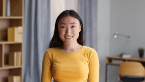 Youth and everyday lifestyle. Close up portrait of young happy asian woman smiling to camera, posing at domestic interior, slow motion