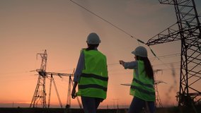 Two civil engineers work together using computer tablet on a power line. Joint work of power engineers with computer in protective helmets, maintenance of power lines in outdoors. Green energy - Powered by Shutterstock - Get 15% off with code: PIKWIZARD15