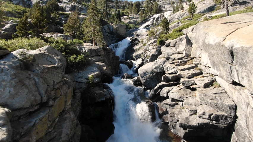 Stabilized 4K cinematic drone flies through the rocky cliffs of an epic waterfall in the desolation wilderness of Lake Tahoe area in California and Nevada.