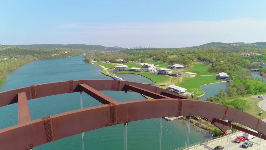 Traffic jam slowly moving across the Pennybacker Bridge with a small view of the city of Austin, Texas. Aerial footage is moving from top to bottom of the video.