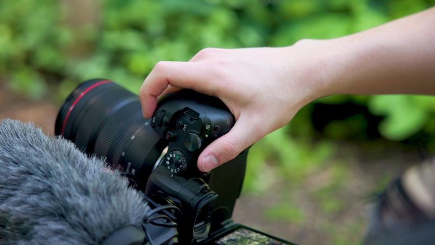 Close up of professional mirrorless camera with microphone shooting photos in a sunny outdoor forest