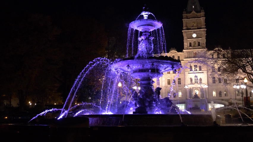 Colorful lights at the Fontaine de Tourny, aka Fontaine de Bordeaux, in Parliament Hill, Quebec City, Canada. With facade of main government building.