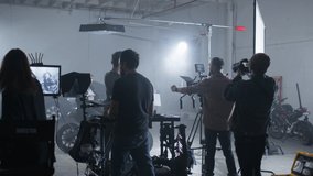 Filmmaking crew filming and audio-recording motion picture. Studio shooting against white background as seen from the backstage. High quality 4k footage