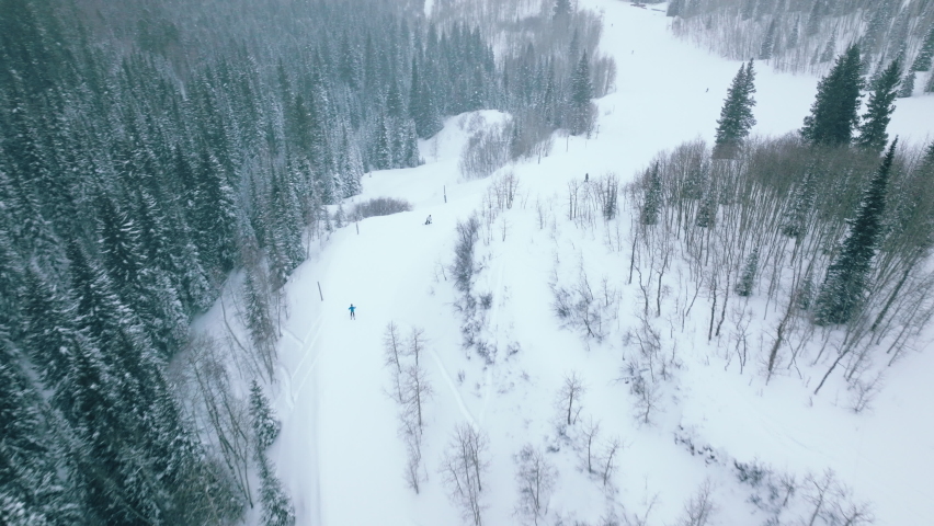 Ski aerial of fast skiers in beautiful mountain forest landscape riding down snowy slope with high speed. Cold winter day high up in mountains, Snowmass ski resort. Ski show great winter panorama 4K Royalty-Free Stock Footage #1092230335