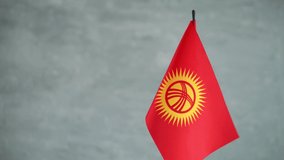 State flag of Republic of Kyrgyzstan waving on light background. Kyrgyz flag and place for text