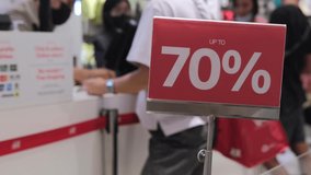 Red sign with a 70 percent discount to attract customers. In the background in blur, unrecognizable customers at the checkout are eager to buy at a bargain price in the store. Discount concept. - Powered by Shutterstock - Get 15% off with code: PIKWIZARD15