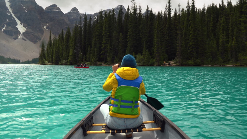 Tourist woman paddling a canoe on Moraine Lake during summer in Banff National Park, Alberta, Canada. Royalty-Free Stock Footage #1092236951