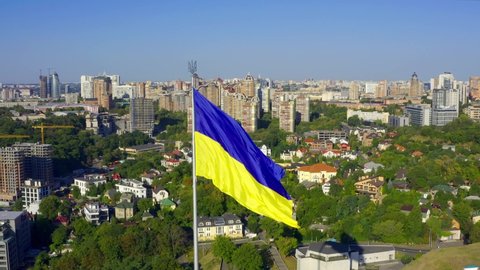 Drone flying around the national flag of  Ukraine near famous monument in Motherland. Cinematic aerial view to national flag of Ukraine in Kiev, in the summer. 