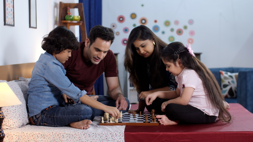An attractive Indian couple and their son and daughter playing a board game - playing chess, an intelligent game. A cheerful modern Indian family - Nuclear Indian family, togetherness and bonding, ... Royalty-Free Stock Footage #1092237407