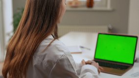 Professional doctor advising pills sitting at laptop with green screen in hospital. Shooting over shoulder of Caucasian young woman consulting online on chromakey device prescribing medication