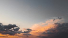 Yellow-orange clouds in sunlight against a dark sky. Time lapse, evening sky at sunset. Weather, cloudy nature background, time lapse. Video, footage for transition or intro. UHD 4K.