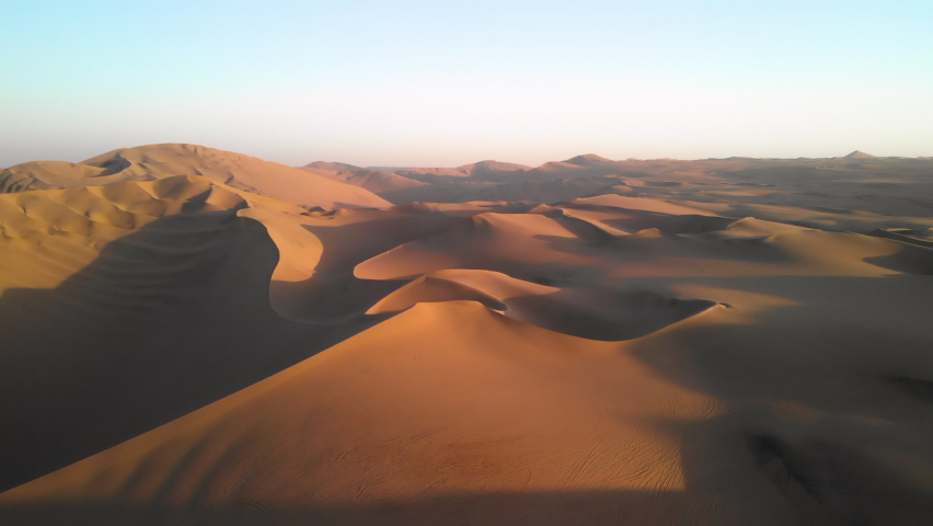 Drone flying high above sand dunes in endless desert landscape of Peru