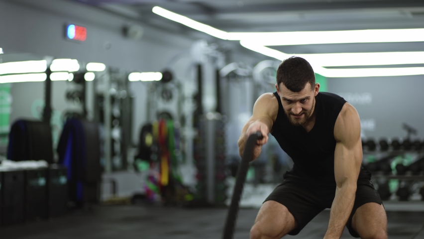 Focused muscular man working out in the gym using battle ropes Royalty-Free Stock Footage #1092263997