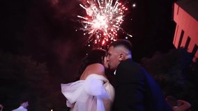 Groom and bride watching fireworks in the sky. Couple in love kiss on the end of wedding day. Excited guests looking at fireshow. - Powered by Shutterstock - Get 15% off with code: PIKWIZARD15