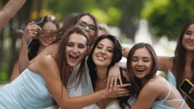 Pretty bridemaids in identical blue dresses run to hug bride together in park cheering waving hands. Woman party with friends on wedding day in elegant airy white gown and long veil. Slow motion - Powered by Shutterstock - Get 15% off with code: PIKWIZARD15