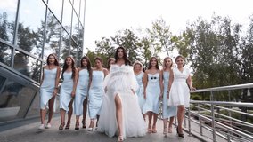 Beautiful bride, pretty bridemaids in pale blue dresses walk cheering waving hands. Woman with long airy bridal veil in elegant fluttering white dress partying flexing with girlfriends. Slow motion. - Powered by Shutterstock - Get 15% off with code: PIKWIZARD15