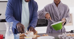 Video of happy african american couple preparing breakfast together in kitchen. Love, relationship and spending quality time together concept.