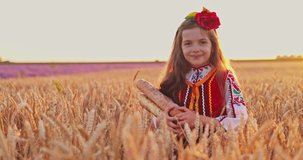 Beautiful girl woman in traditional Bulgarian folklore dress holding homemade bread in wheat field, agriculture and homegrown food concept