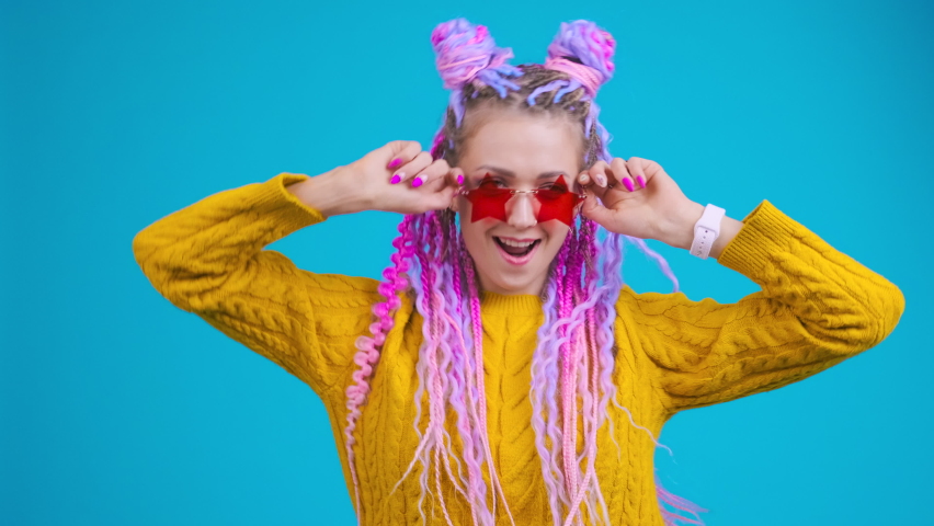 Funny young woman dancing moving her head, excited and emotional person. Creative person with colorful hair and afro braids dreadlocks wear star shape glasses, positive emotion, ecstatic feeling Royalty-Free Stock Footage #1092271583