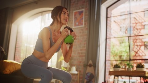 Home Gym Training: Beautiful Fit Asian Woman Lifting Heavy Kettlebell, Does Endurance Exercise. Strong Sportswoman doing Workout. Energetic Action. Immersive Low Angle Portrait, Slow Motion Shot