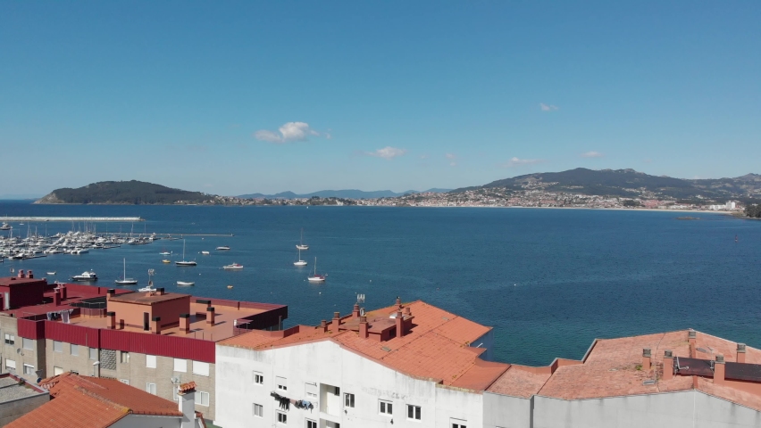 An aerial introduction to the Harbor of Baiona, Galicia, Spain.Baoina's Castle (Parador de Baiona) visible at the bottom. A popular and highly visited European travel destination. Royalty-Free Stock Footage #1092276913