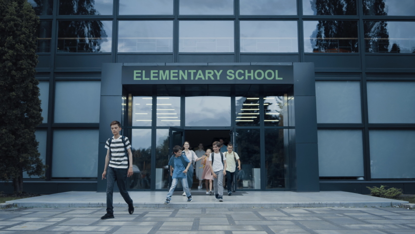 Diverse pupils leaving elementary school building. Happy children talking smiling walking outside. Group of cheerful energetic students with backpacks going out modern campus. Childhood concept. Royalty-Free Stock Footage #1092280765