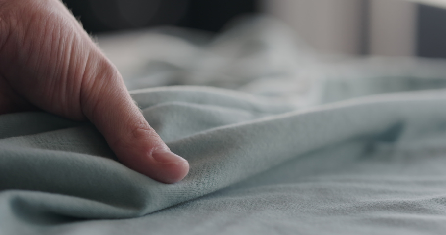 Slow motion man touching cyan cotton clothes closeup