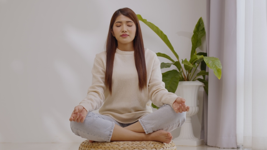 Asian woman practice yoga lotus pose to meditation at home.
