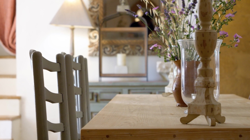 Dining room table with flower vases and different set chairs on sides at a villa in Southern France, Dolly right close up shot