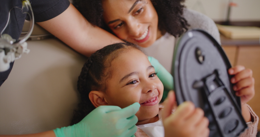 Learning about oral and dental hygiene. Dentist examining little girls teeth and mouth during dental appointment. Child looking in mirror and having her checkup to prevent tooth decay and gum disease Royalty-Free Stock Footage #1092296455