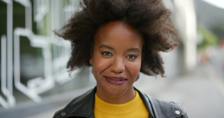 Face of an edgy young woman with afro smiling. Portrait of beautiful trendy black girl laughing, showing her teeth. Confident attractive African American female with positive attitude in the street Royalty-Free Stock Footage #1092296743