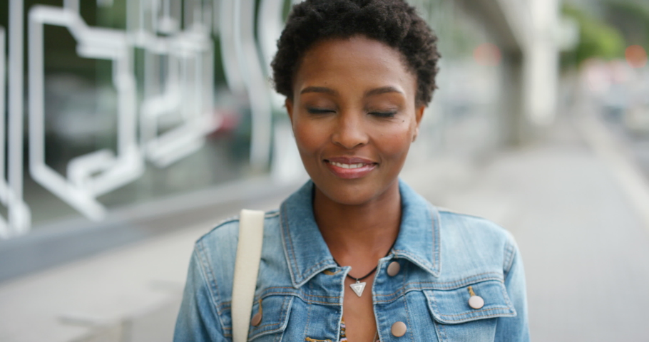 Portrait of a young beautiful woman having fun in city on the weekend. One smiling black female with an afro enjoying a day in town. Gorgeous woman showing her teeth and taking care of dental hygiene Royalty-Free Stock Footage #1092297077