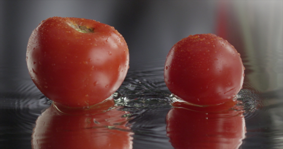 Two tomatoes slide across the frame