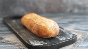 Woman slashes baguette bread on cutting board with knife