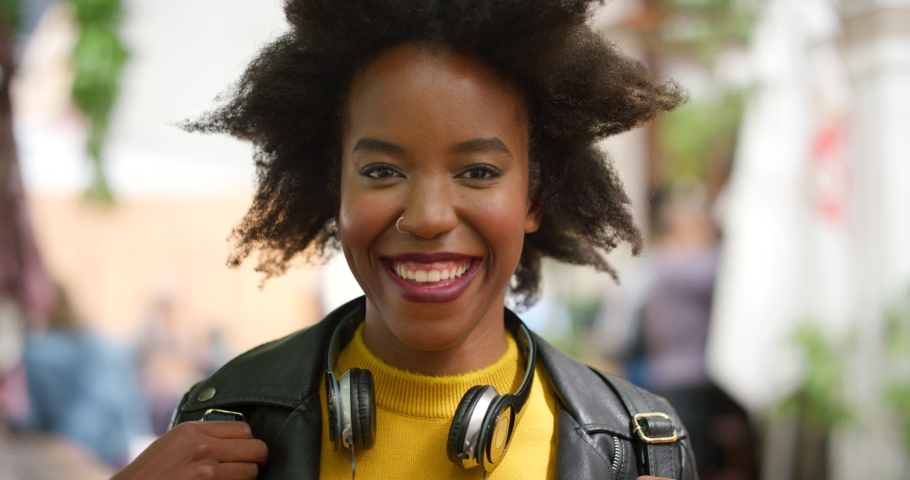 Closeup portrait of a happy, stylish and trendy woman laughing while commuting in the city alone. Headshot of a beautiful, edgy female with an afro laughing and looking confident downtown Royalty-Free Stock Footage #1092305349