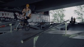 Young male hipster riding on bmx bike at urban space. Closeup bmx rider performing extreme tricks on rail at skate park. Casual biker training skills outdoors. Active leisure time outside concept. - Powered by Shutterstock - Get 15% off with code: PIKWIZARD15