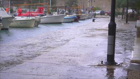 Small boats in a harbor in a town.Rainy weather. Water goes up and reaches the walkway due to the sea level rise. Coastal cities flooding concept. Global warming concept - Powered by Shutterstock - Get 15% off with code: PIKWIZARD15