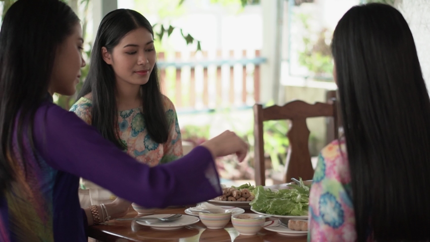 Vietnamese beautiful women in traditional costumes eat food Vietnamese Meatball Wraps (Nam Neung)enjoying with eat healthy tradition Vietnam food with friend concept. | Shutterstock HD Video #1092314677