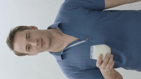 Young man with glass of milk on white background. The man shows that drinking milk is healthy.Being healthy. The power of calcium.Video for the vertical story.