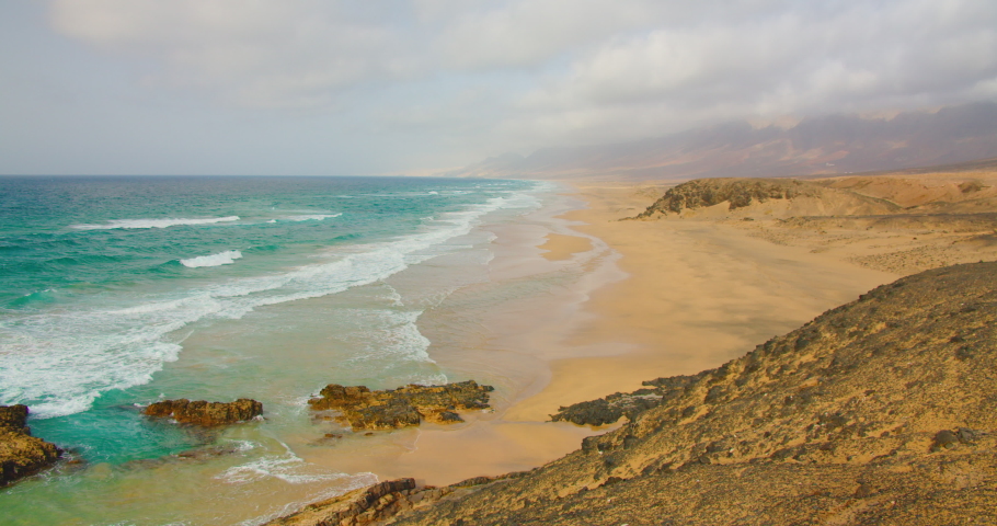 Incredibly beautiful empty long sandy smooth beach at sunrise, Cofete, Corralejo, Fuerteventura. Calm transparent azure turquoise water and no people